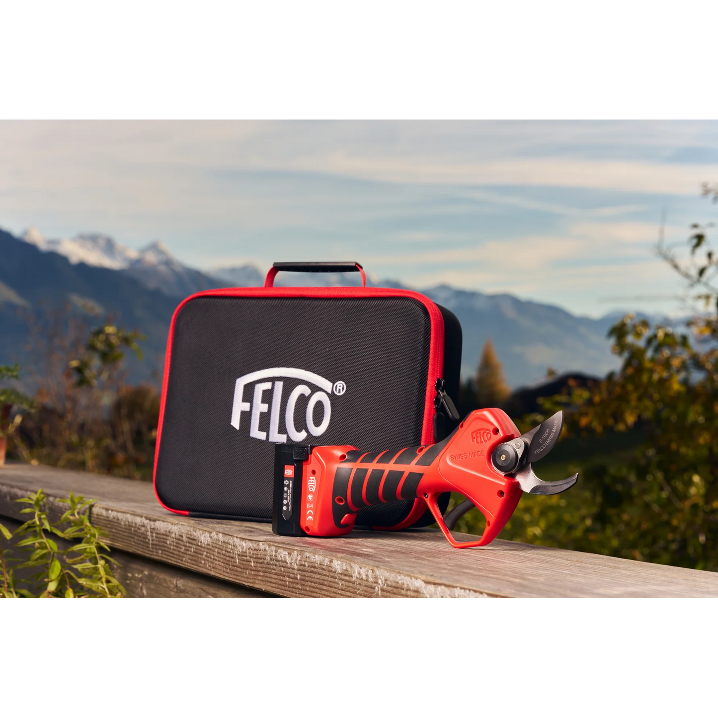 FELCO 2e Electric Pruner with CUT SHIELD™ Safety resting on a wooden surface beside its protective case.