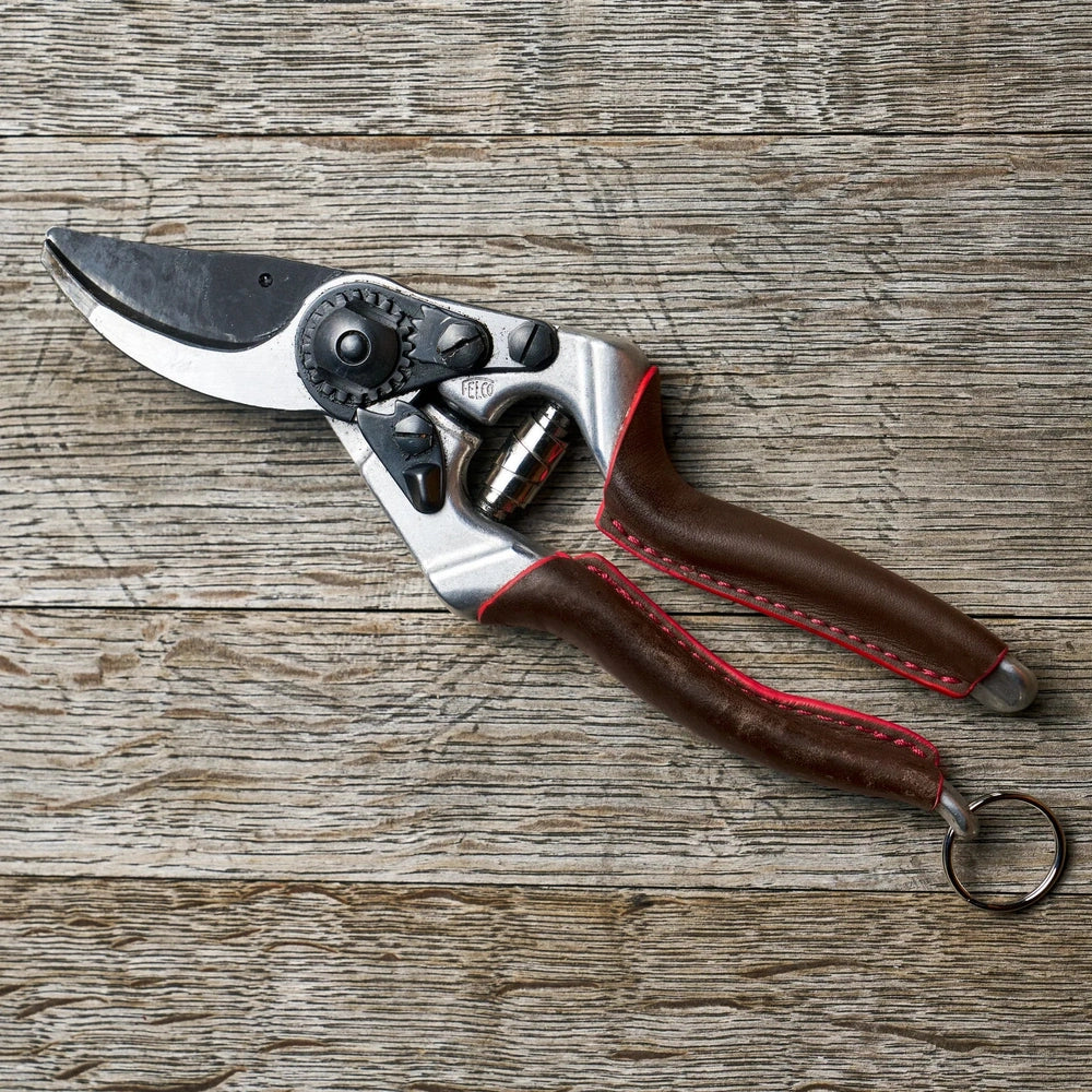 Felco 8 Elite F-8ELITE pruning shears with ergonomic design and angled cutting head on wooden background.