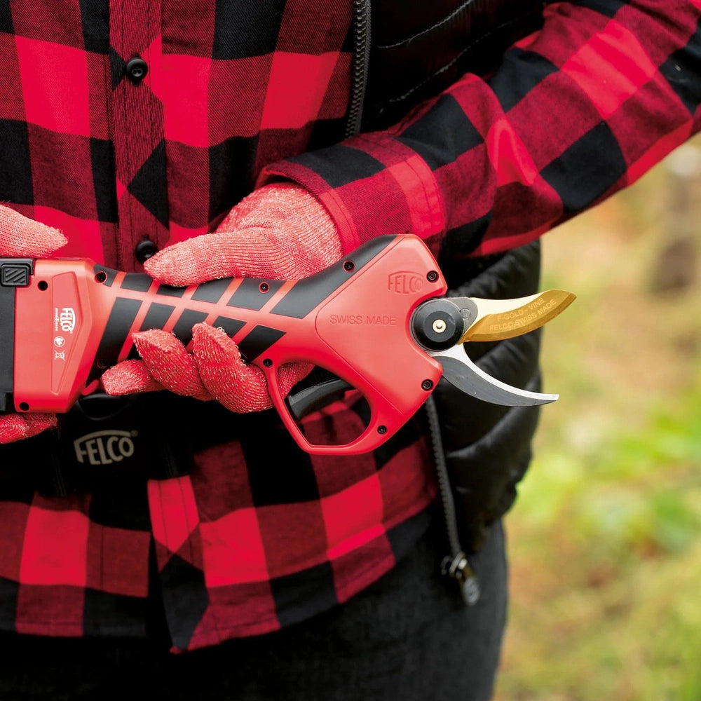 Felco 834V electric pruning shear held by a person in a checkered shirt, designed for vineyard maintenance.
